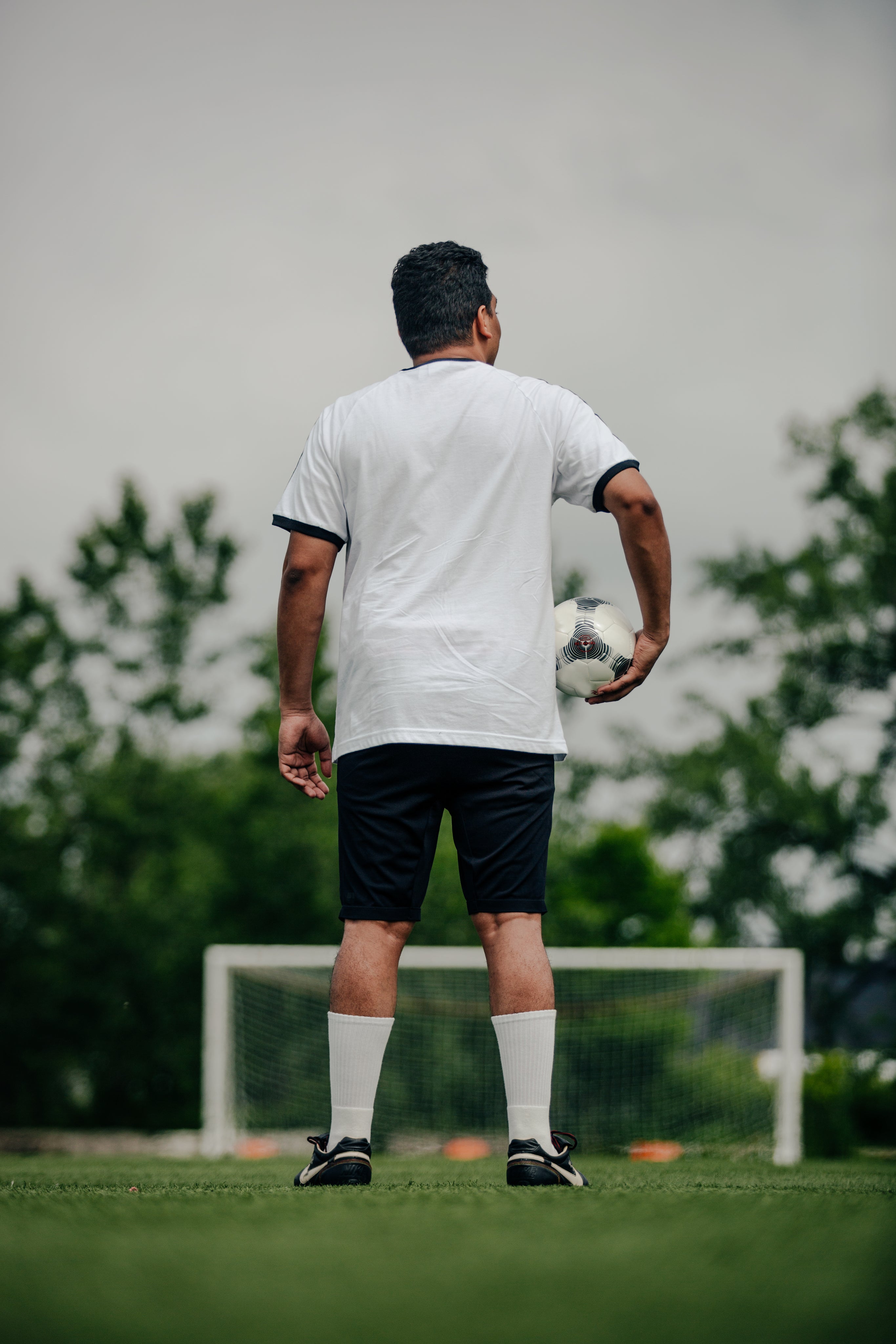 Soccer player holding a ball on an empty field