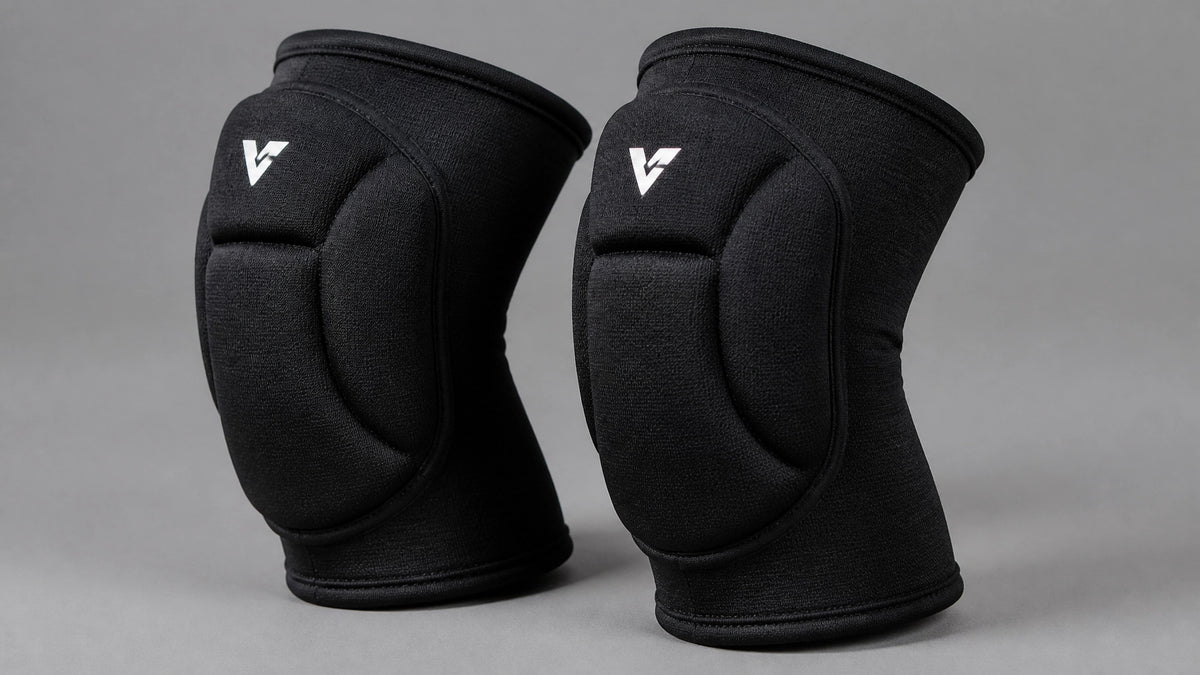 A pair of black padded volleyball knee pads standing upright against a plain gray studio background
