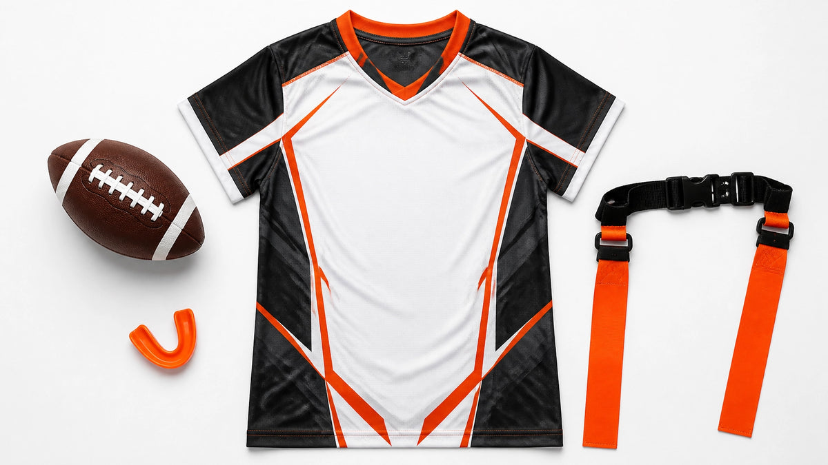 A football, orange mouthguard, black and white flag football jersey, and a flag belt laid out on white