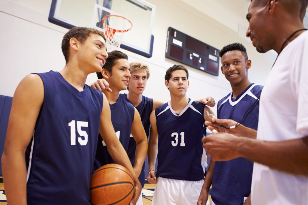 Custom Basketball Uniforms: What to Look For (and How to Order for Your Team) 1 male high school basketball team having team talk with coach scaled